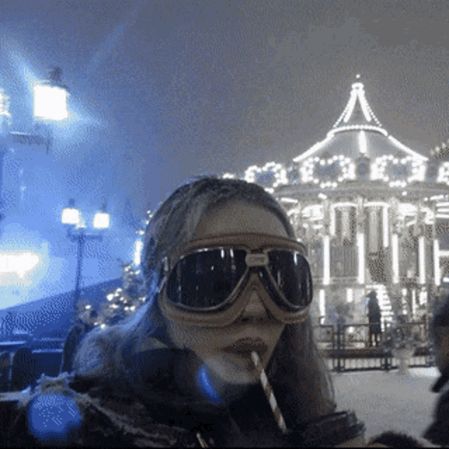 a woman wearing goggles drinks through a straw