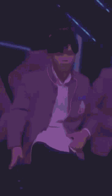 a man in a grey jacket and white shirt is standing on a stage .