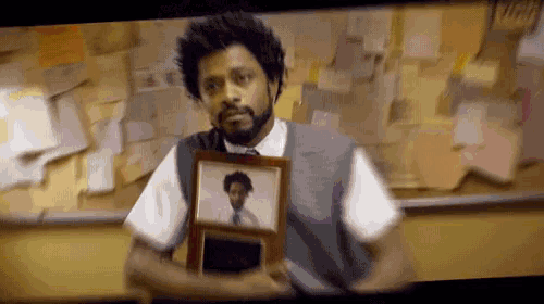 a man with a beard is holding two framed pictures