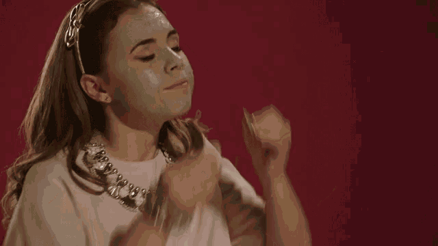 a woman is wearing a mask on her face and covering her eyes with her hands .