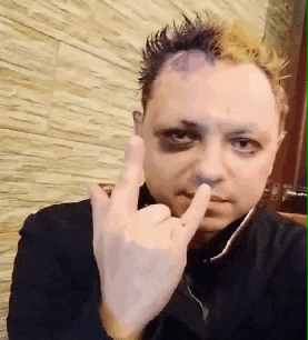 a man with a black eye is making a devil horns sign with his fingers
