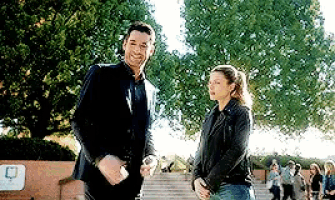 a man and woman are standing next to each other in front of a tree .