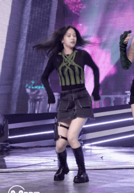 a girl in a green and black outfit is dancing