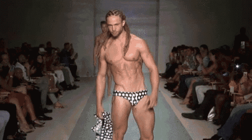 a man is walking down the runway at a fashion show wearing polka dot swim trunks