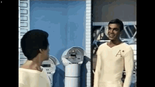 a man in a white shirt with the letter a on it stands next to another man