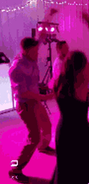 a man and a woman are dancing in a room with pink lights