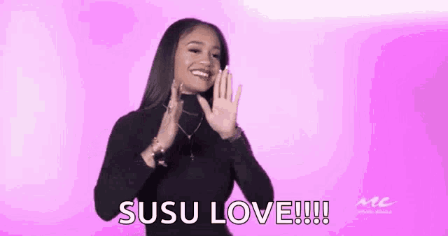 a woman in a black turtleneck is smiling and holding her hands up in the air .