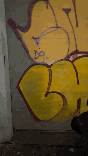 a person is painting graffiti on a wall with the letter m