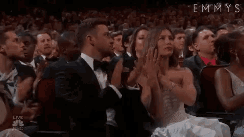 a man and a woman are sitting in a crowd of people clapping .