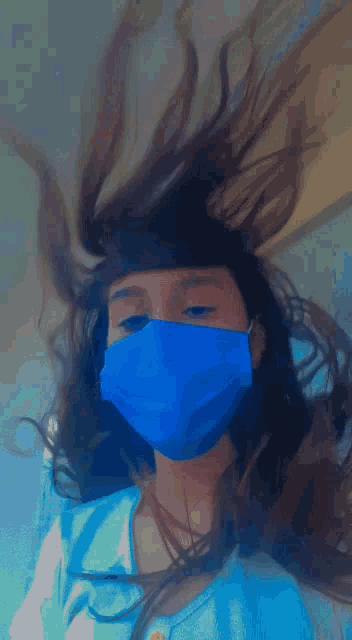 a girl wearing a blue mask has her hair blowing in the wind