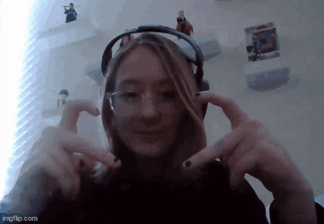 a girl wearing headphones making a heart with her hands