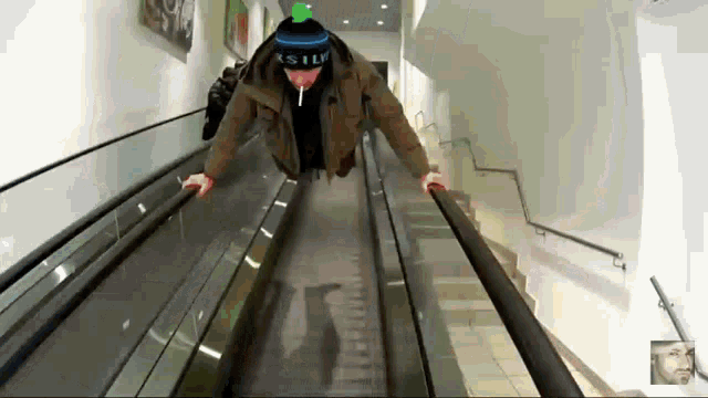 a man wearing a hat that says ' xslv ' on it rides an escalator