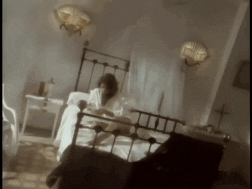 a woman is laying in a bed with a cross on the wall behind her