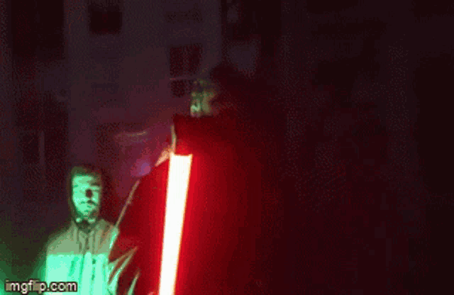 a person is holding a red light saber in their hand in a dark room .