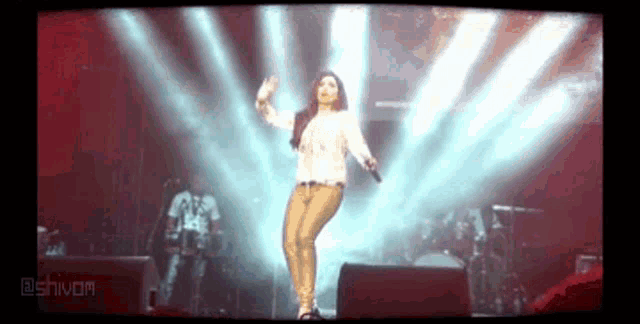a woman is dancing on stage with a microphone in her hand .