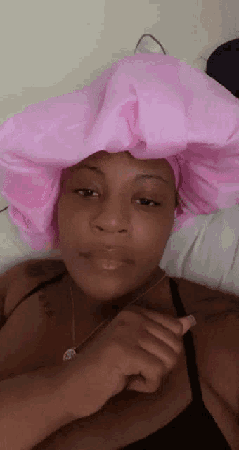 a woman with a pink hat on her head is laying on a bed