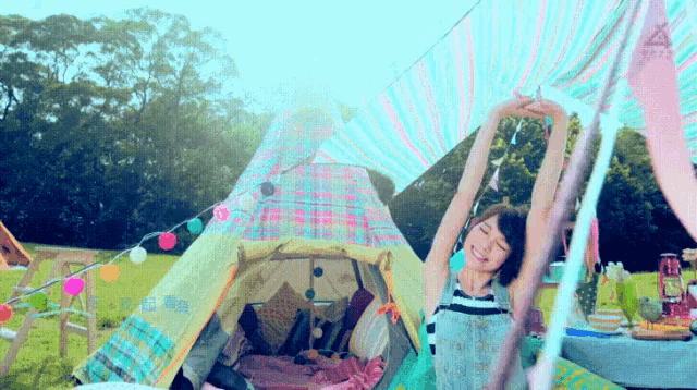 a woman is stretching her arms in front of a teepee .