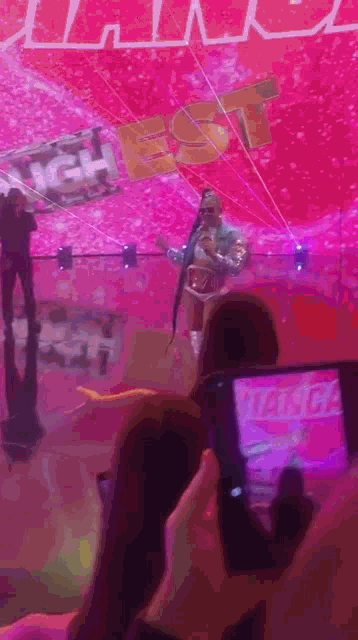a person taking a picture of a person on stage with a sign that says highest on it