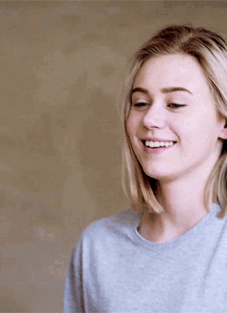 a woman wearing a grey sweater is smiling and looking to the side