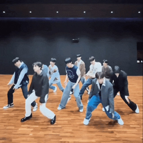 a group of young men are dancing on a wooden floor in a room .