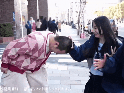 a man in a pink plaid sweater is being kissed by a woman in a blue jacket