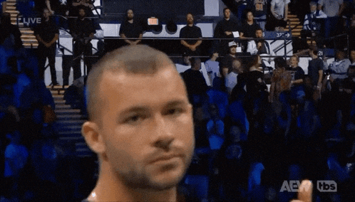 a man giving a thumbs up in front of a crowd with aew written on the bottom right