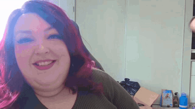 a woman with red hair is smiling in front of a wall