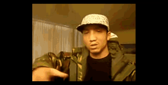 a man wearing a hat with the word adidas on it is pointing