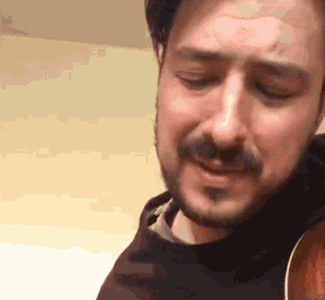 a man with a beard is holding a guitar and singing