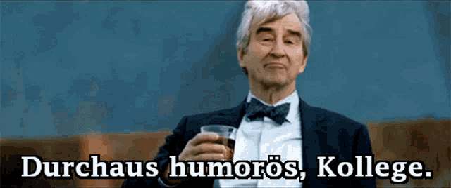 a man in a suit and bow tie is holding a glass of whiskey