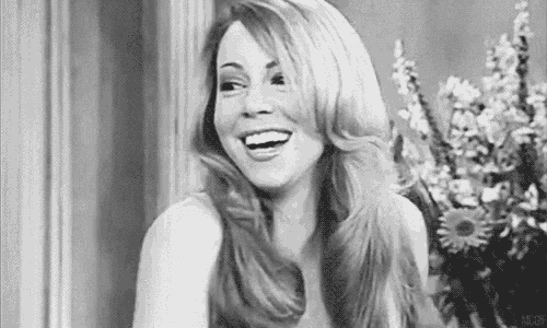 a black and white photo of a woman smiling in front of a vase of flowers .