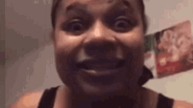 a woman is making a funny face in front of a camera in a dark room .