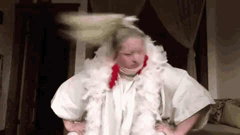 a woman in a white dress and feather boa is standing in a living room .