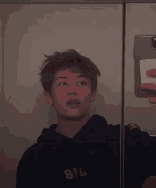 a young man is taking a picture of himself in a mirror with his phone .