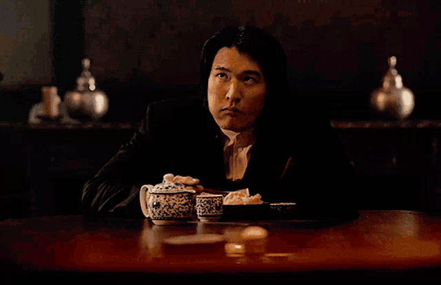 a man in a suit sits at a table with two bowls of food in front of him