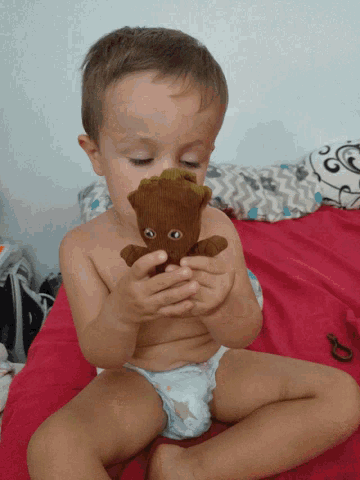 a baby in a diaper holds a stuffed animal