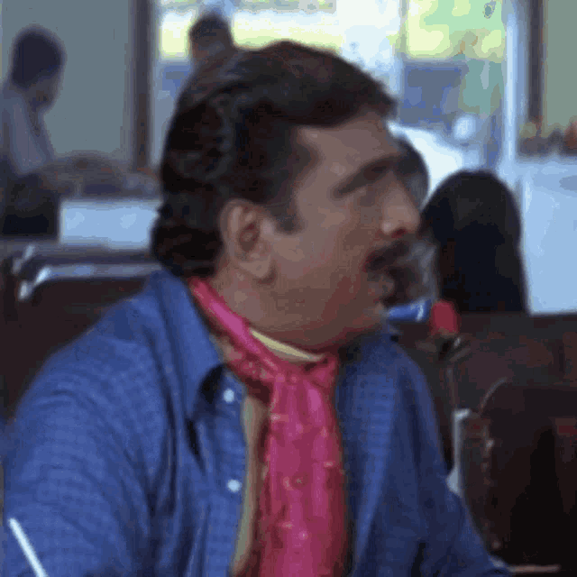 a man wearing a blue shirt and a pink scarf is sitting in a restaurant