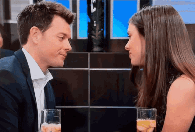 a man in a suit and a woman in a black dress look at each other