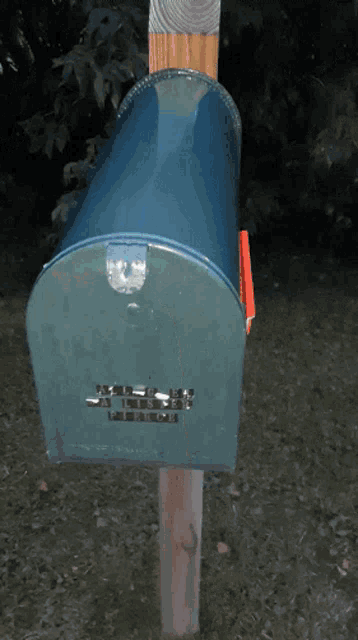 a blue mailbox is sitting on a wood post
