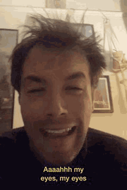 a man with a beard is smiling and making a funny face .