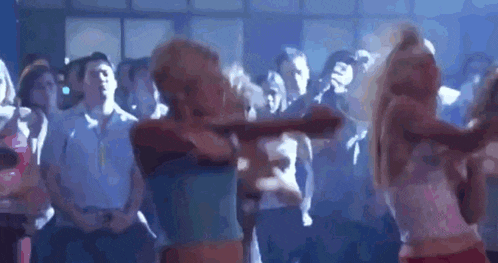 a group of people are dancing in a dark room in front of a crowd .