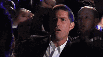 a man in a suit is sitting in a crowd of people .