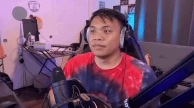 a man wearing headphones is sitting in a chair in front of a microphone .