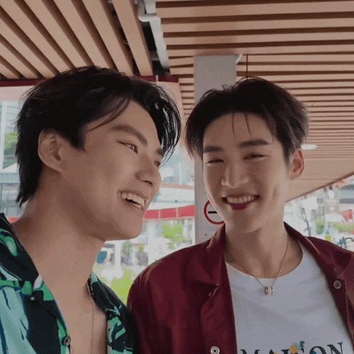 a man wearing a shirt that says maison is smiling next to another man