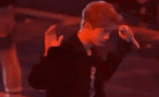 a man is standing in front of a microphone in a dark room with red lights .
