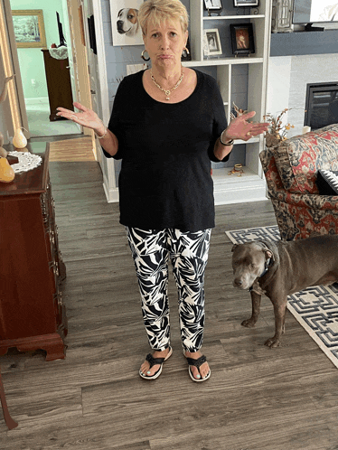 a woman standing in a living room with a dog standing next to her