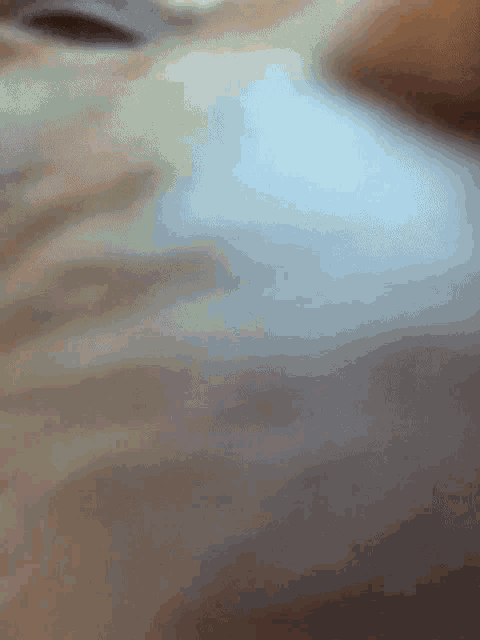 a blurred image of a person 's face with a blue sky in the background
