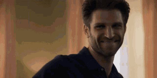 a man with a beard wearing a black shirt is smiling .