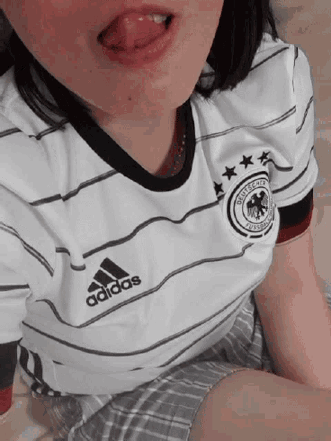 a woman is sticking her tongue out while wearing an adidas jersey