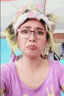 a woman wearing glasses and a headband is making a face